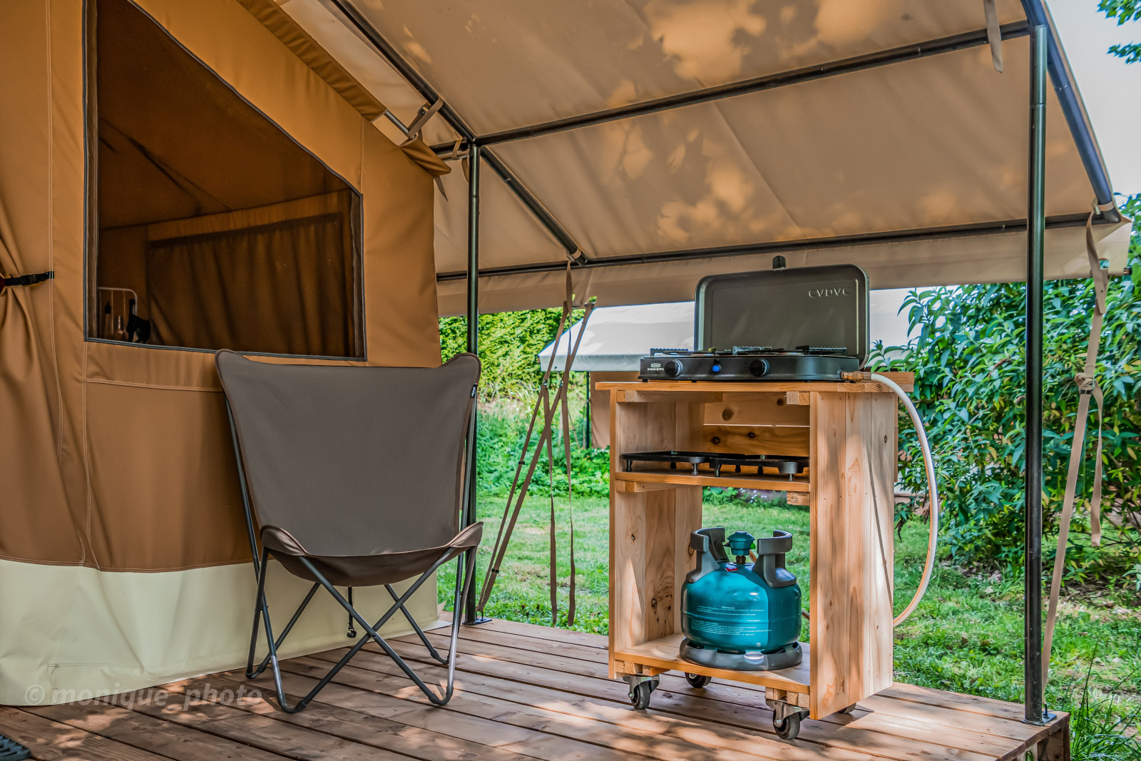 Safaritent Ponza met klapstoel, buitenkeuken en gasfles op houten vlonder onder een luifel.