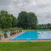 Outdoor swimming pool at Onlycamp Camping de Besançon surrounded by trees in Bourgogne-Franche-Comté, France.