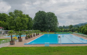 Außenpool bei Onlycamp Camping de Besançon, umgeben von Bäumen, in Bourgogne-Franche-Comté, Frankreich.
