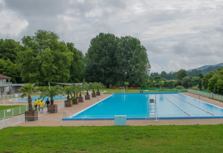 Outdoor swimming pool at Onlycamp Camping de Besançon surrounded by trees in Bourgogne-Franche-Comté, France.