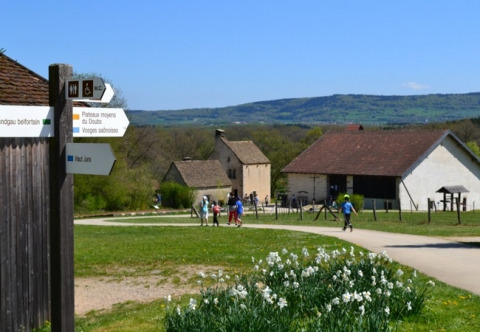 Ferienpark in Bourgogne-Franche-Comté, Frankreich, mit Häusern, Schildern, Blumen und wandernden Familien.
