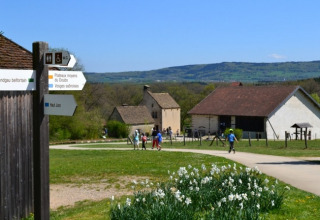 Vakantiepark in Bourgogne-Franche-Comté, Frankrijk, met huisjes, paden, bloemen en wandelende bezoekers.