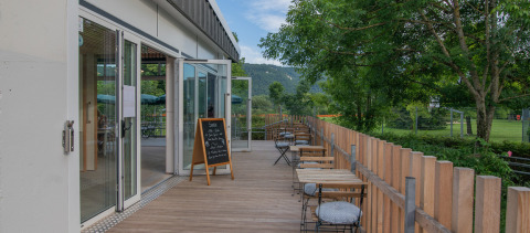 Outdoor terrace with tables and chairs overlooking greenery at Onlycamp Camping de Besançon in France.