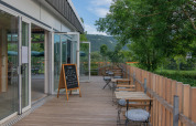 Sonnige Terrasse mit Sitzplätzen und Blick ins Grüne im Onlycamp Camping de Besançon, Frankreich.