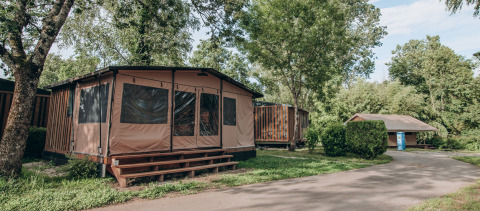 Cabañas tipo tienda y vegetación en Onlycamp Camping de Besançon, parque vacacional en Bourgogne-Franche-Comté, Francia.