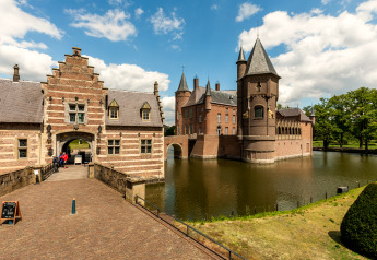 Beautiful photograph of a historic lodge surrounded by a moat, with visitors entering through the gate.