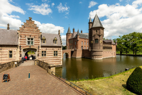Beautiful photograph of a historic lodge surrounded by a moat, with visitors entering through the gate.