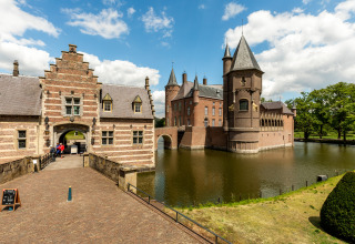 Beautiful photograph of a historic lodge surrounded by a moat, with visitors entering through the gate.