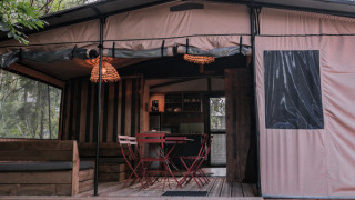Gemütliches Chalet Galli Tiny House mit Terrasse und Sitzbereich, umgeben von grüner Natur und Bäumen.