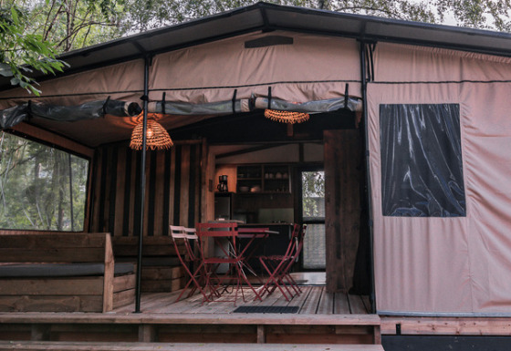 Gemütliches Chalet Galli Tiny House mit Terrasse und Sitzbereich, umgeben von grüner Natur und Bäumen.