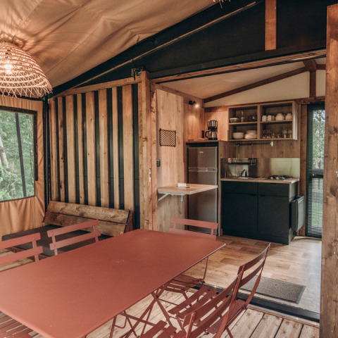 Innenansicht eines gemütlichen Tiny House mit Küche, Esstisch und Holzeinrichtung im Chalet Galli, Frankreich.