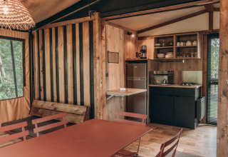 Innenansicht eines gemütlichen Tiny House mit Küche, Esstisch und Holzeinrichtung im Chalet Galli, Frankreich.