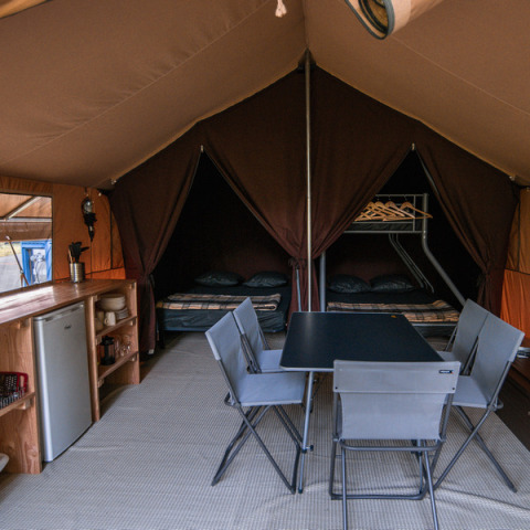 Innenansicht des Ponza-Safarizeltes bei Onlycamp Camping de Besançon mit Tisch, Stühlen und Betten.