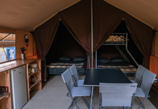 Innenansicht des Ponza-Safarizeltes bei Onlycamp Camping de Besançon mit Tisch, Stühlen und Betten.