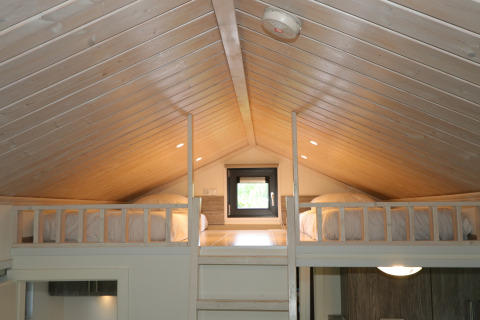 Slaapzolder met twee bedden en houten plafond in Tiny Lodge bij De Wije Werelt, Nederland.