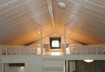 Chambre mezzanine avec deux lits et plafond en bois dans la Tiny Lodge à De Wije Werelt, Pays-Bas.