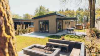 Lodge Loevestein Deluxe moderno con jacuzzi, patio, área de descanso y jardín rodeado de naturaleza.