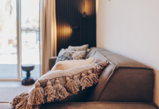 Canapé confortable avec coussin à pompons chez Loevestein Deluxe, Veluwe park de Bosgraaf, Pays-Bas.