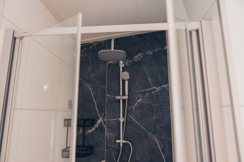 Douche moderne avec portes en verre, mur en marbre foncé et pommeau pluie à Loevestein Deluxe, Veluwe park de Bosgraaf.