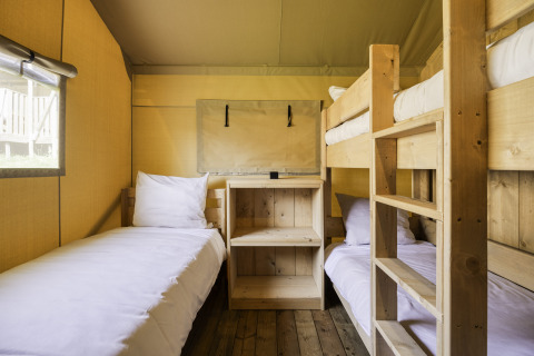 Interieur van safaritent Sunshine 49 in Petite Suisse, België, met een eenpersoonsbed en stapelbed.