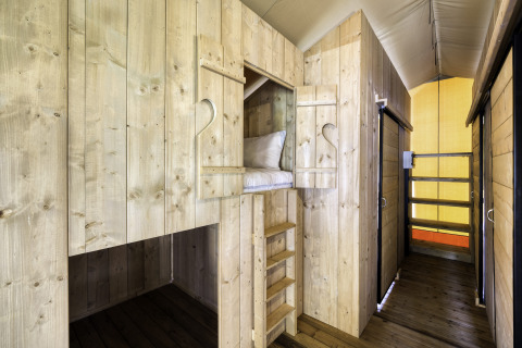Interieur van safaritent 'Sunshine 49' bij Petite Suisse in België met houten stapelbedden en gezellige sfeer.