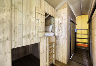 Interieur van safaritent 'Sunshine 49' bij Petite Suisse in België met houten stapelbedden en gezellige sfeer.