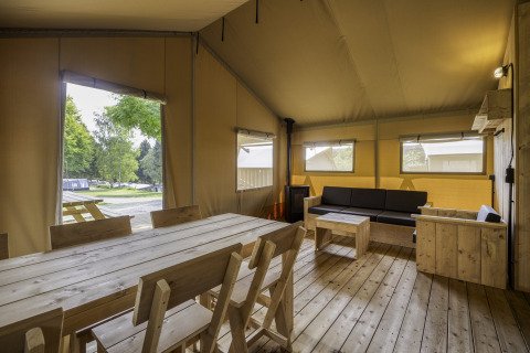 Interieur van safaritent Sunshine 49 bij Petite Suisse in België met houten meubels en zithoek.