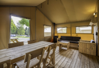 Interieur van safaritent Sunshine 49 bij Petite Suisse in België met houten meubels en zithoek.
