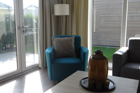 Helles Wohnzimmer in Lodge 4, Breeduyn Village, Belgien, mit blauen Sesseln und großen Fenstern.