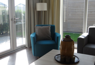 Helles Wohnzimmer in Lodge 4, Breeduyn Village, Belgien, mit blauen Sesseln und großen Fenstern.
