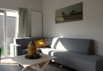 Modernes Wohnzimmer in Lodge 4, Breeduyn Village, Belgien, mit grauem Sofa, Couchtisch und Wandbild.