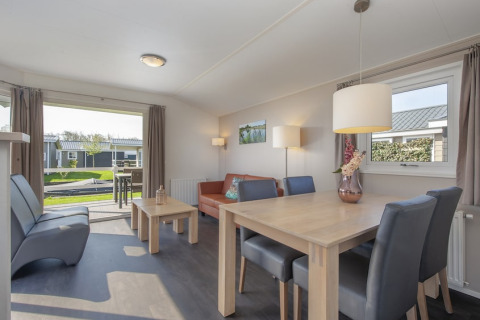 Lyst opholdsrum i lodge Meerkoet 4 i Giethoorn, Holland, med moderne møbler og udsigt til terrasse.