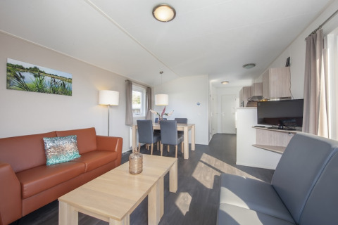 Lys stue med moderne møbler i Meerkoet 4-lodge i Giethoorn, Holland, med spisebord og sofaer.