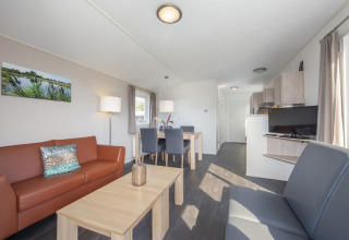 Lys stue med moderne møbler i Meerkoet 4-lodge i Giethoorn, Holland, med spisebord og sofaer.