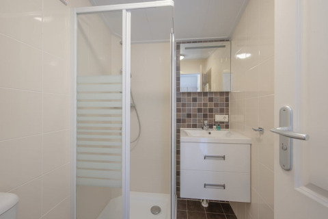 Modernes Badezimmer mit Dusche, Waschbecken und Spiegel in der Stern 6 Lodge, Giethoorn, Niederlande.
