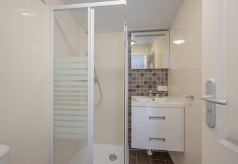 Modern bathroom with shower enclosure, sink, and mirror in Stern 6 Lodge, Giethoorn, Netherlands.