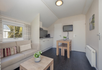 Interior of Tiny House 2 in Giethoorn, Netherlands, with sofa, small kitchen, dining table, and TV.