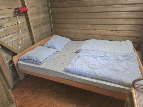 Innenaufnahme eines schlichten Doppelbetts mit zwei Kissen in der Writer's Cabin in Zomerlicht, Niederlande.
