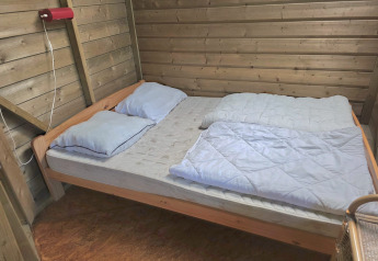 Vista interior de una cama doble sencilla con dos almohadas en Writer's Cabin, Zomerlicht, Países Bajos.
