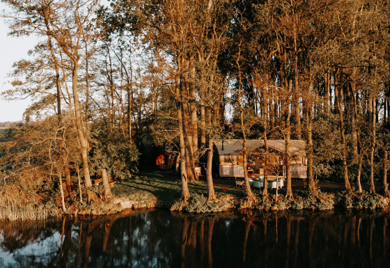 Het Glamphuys Ultra Wellness safaritent staat tussen bomen aan een meer, helemaal omgeven door natuur.