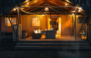 Oplyst safaritelt 'Glamphuys Ultra' ved Ruysbos, Holland, med bål og hyggelige lyskæder om aftenen.
