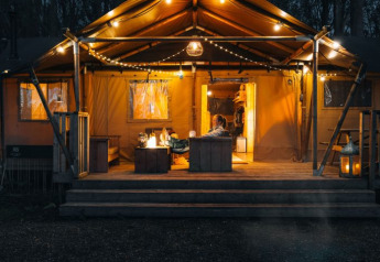 Oplyst safaritelt 'Glamphuys Ultra' ved Ruysbos, Holland, med bål og hyggelige lyskæder om aftenen.