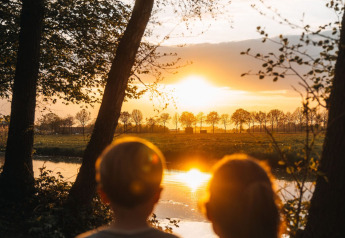 Two children admire the river sunset at the Glamphuys Ultra safari tent on Ruysbos Estate, Netherlands.