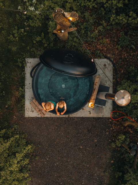 Luchtfoto van twee kinderen in een ronde hottub bij Glamphuys Ultra safaritent op Ruysbos domein, Nederland.