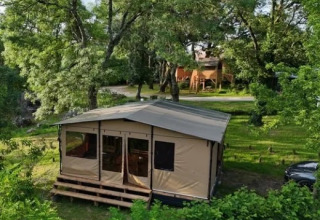 Blik på teltlignende feriebolig blandt grønne træer i Onlycamp Camping Les Thézières, Auvergne-Rhône-Alpes.
