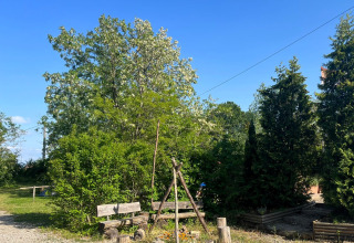 Camping Vauban in Grand Est, Frankreich, mit Holzbänken und Lagerfeuerplatz im grünen Gartenbereich.