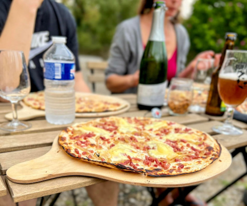 Udendørs middag på Camping Vauban i Grand Est, Frankrig, med pizzaer og drikkevarer på bordet.