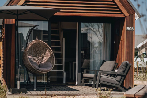 Udendørsområde ved et moderne tiny house i Nieuwvliet-Bad, Holland, med hyggelige stole og hængestol.