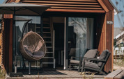 Espace détente extérieur d’une tiny house à Nieuwvliet-Bad, Pays-Bas, avec fauteuil suspendu au soleil.