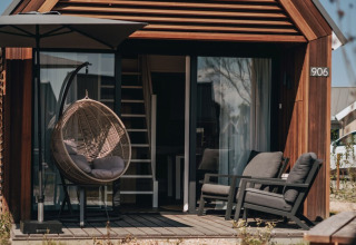 Udendørsområde ved et moderne tiny house i Nieuwvliet-Bad, Holland, med hyggelige stole og hængestol.